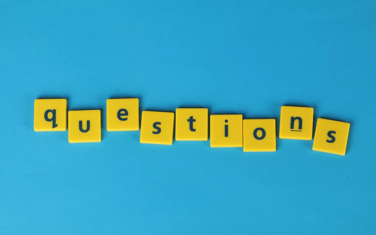 Napis questions z żółtych klocków na niebieskim tle